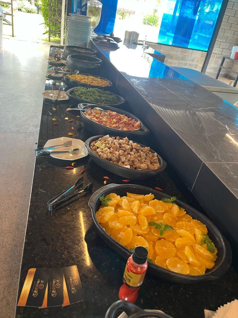 Buffet montado com feijão tropeiro, tutu, saladas e frutas em uma confraternização